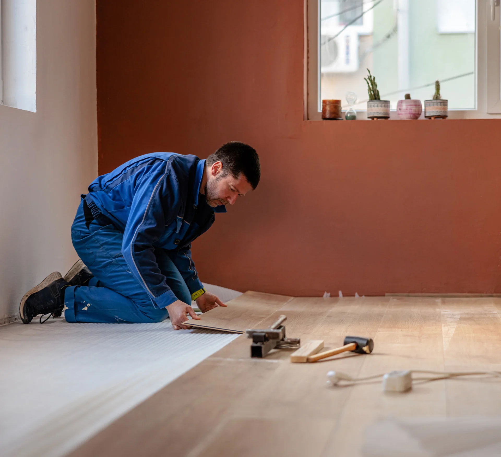 Person installing wooden flooring in room.