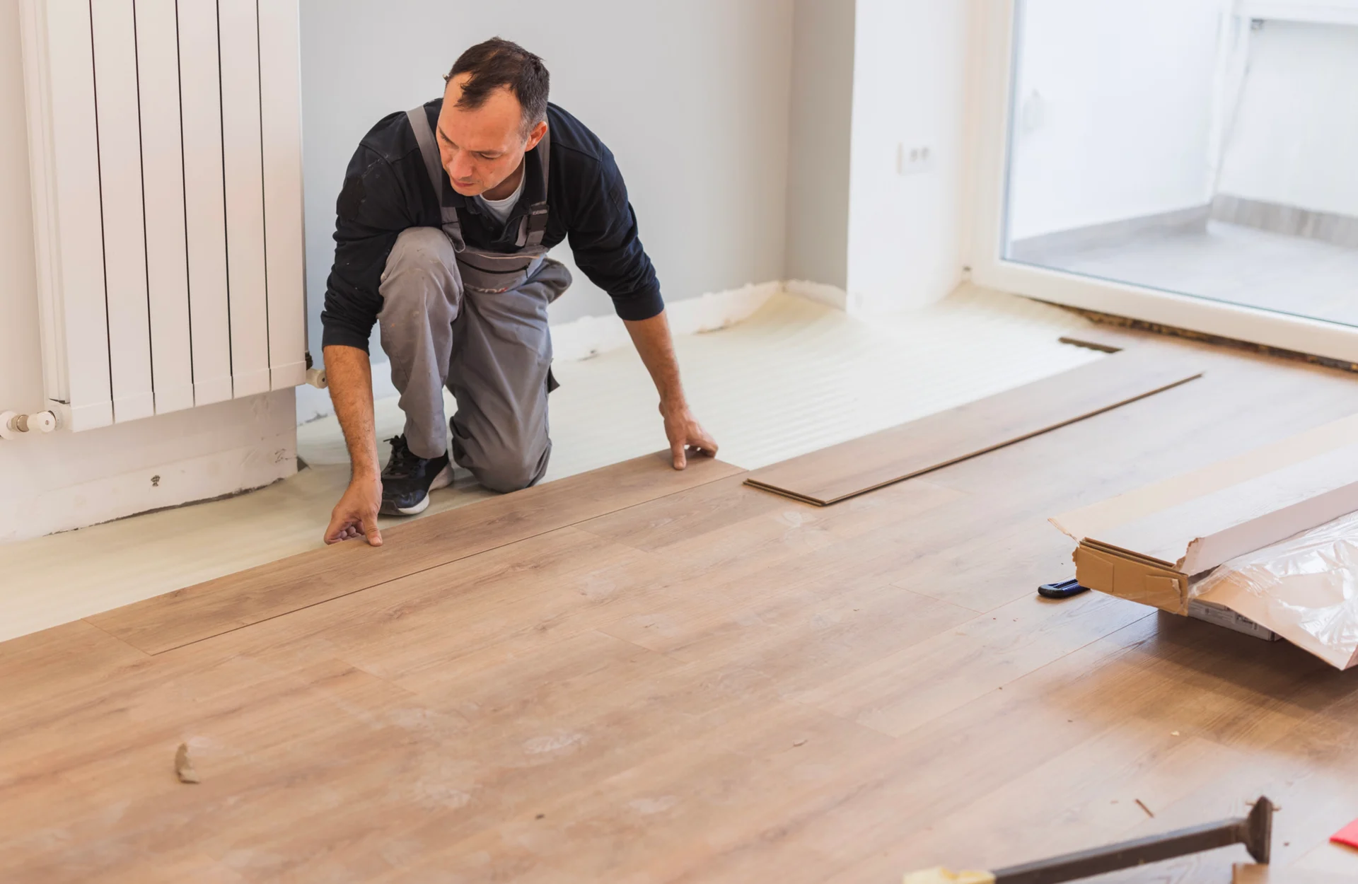 Man installing wooden floor panels indoors.