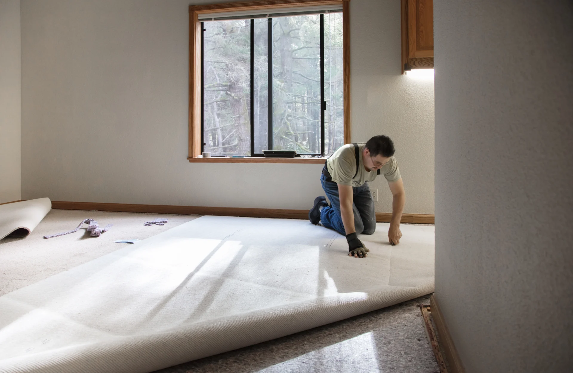 Man installing carpet in a room.