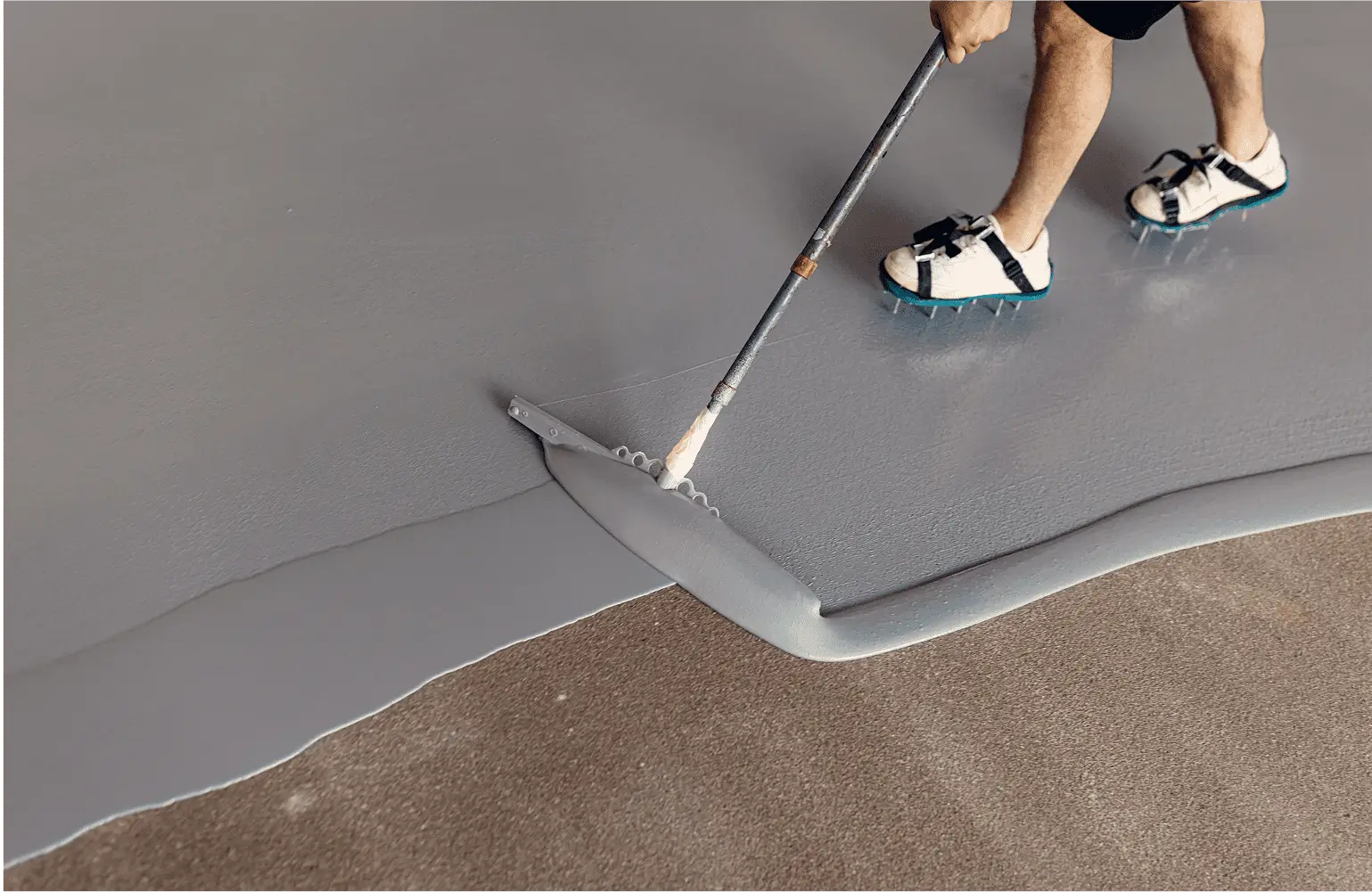 Applying gray epoxy coating on concrete floor.