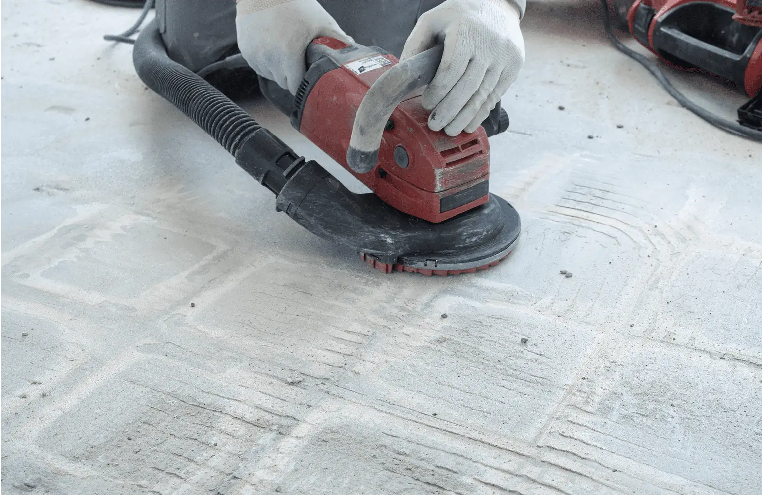 Worker using floor grinder on concrete surface.